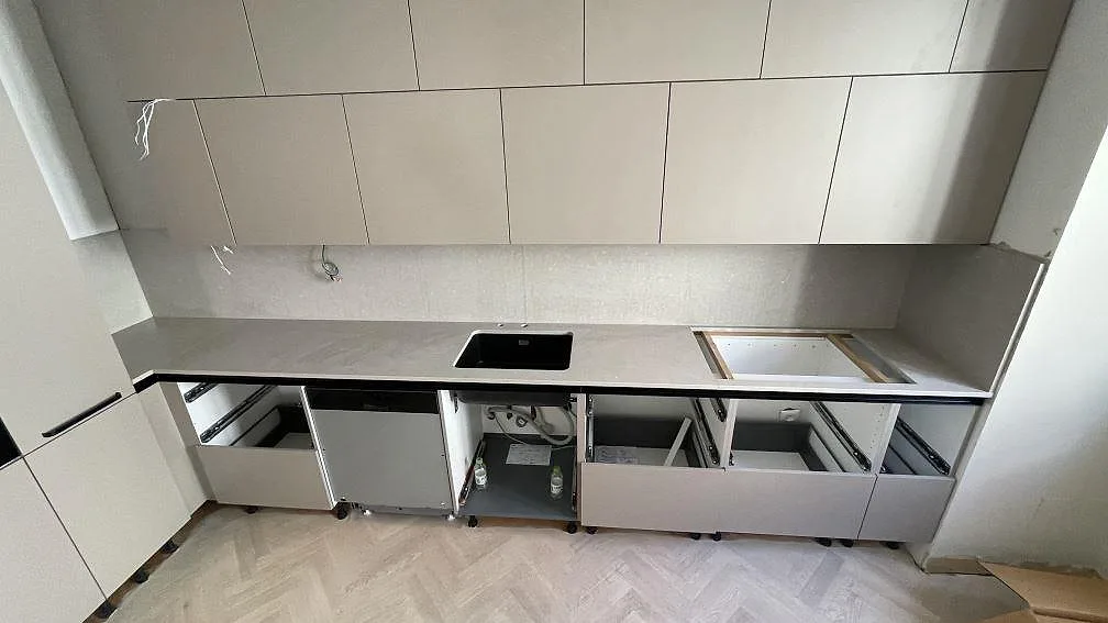 Rak köksbänkskiva i matt Caesarstone Clamshell komposit med stänkskydd, svart diskho och förberedd hällöppning i ett kök i Malmö.