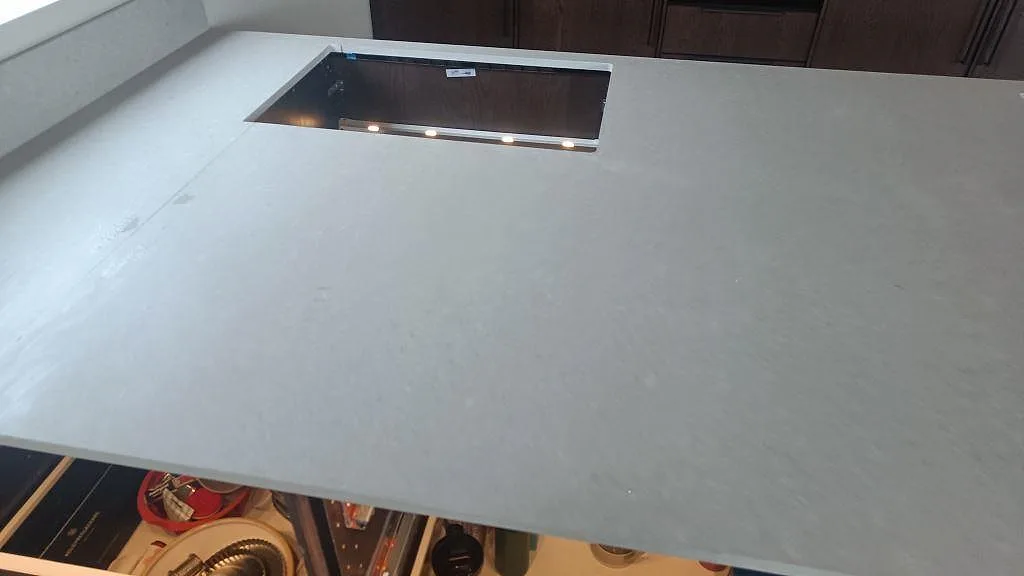 Köksbänkskiva i matt Caesarstone Clamshell med större förberett urtag och mörk köksinredning under montering i Nättraby.