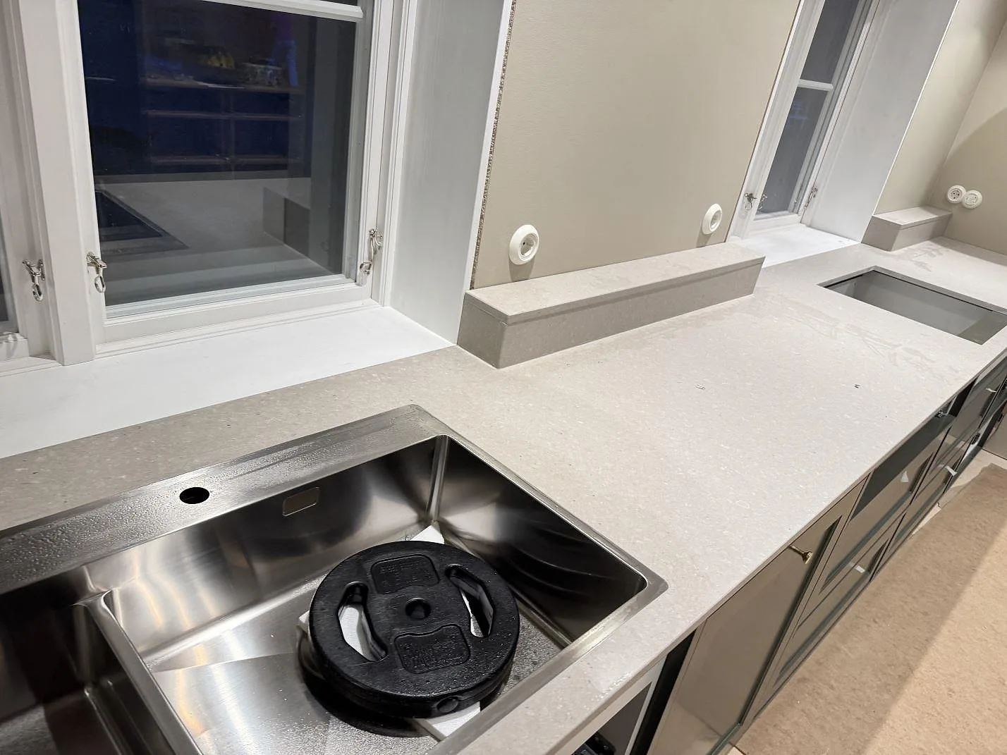 Köksbänkskiva i matt Caesarstone Clamshell kvartskomposit med rostfri diskho, låg stänkkant och hällöppning i ett kök i Osby.