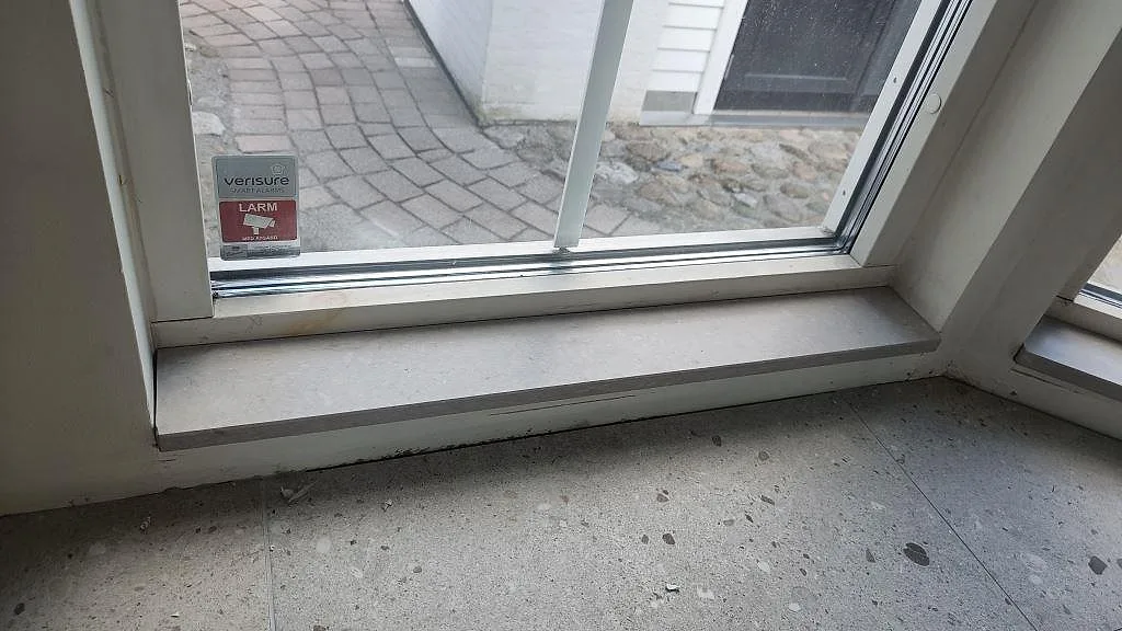 Fönsterbänk i matt Caesarstone Clamshell vid hörnfönster och grått golv i Södra Sandby.