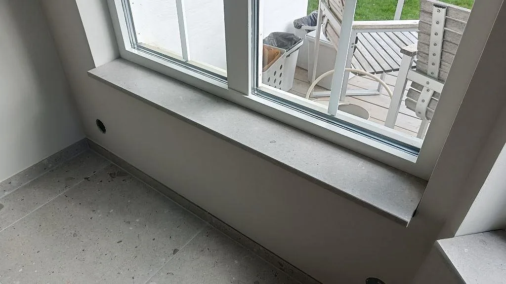 Fönsterbänk i Caesarstone Clamshell, matt kvartskomposit, vid matplats och stora fönster i Södra Sandby.