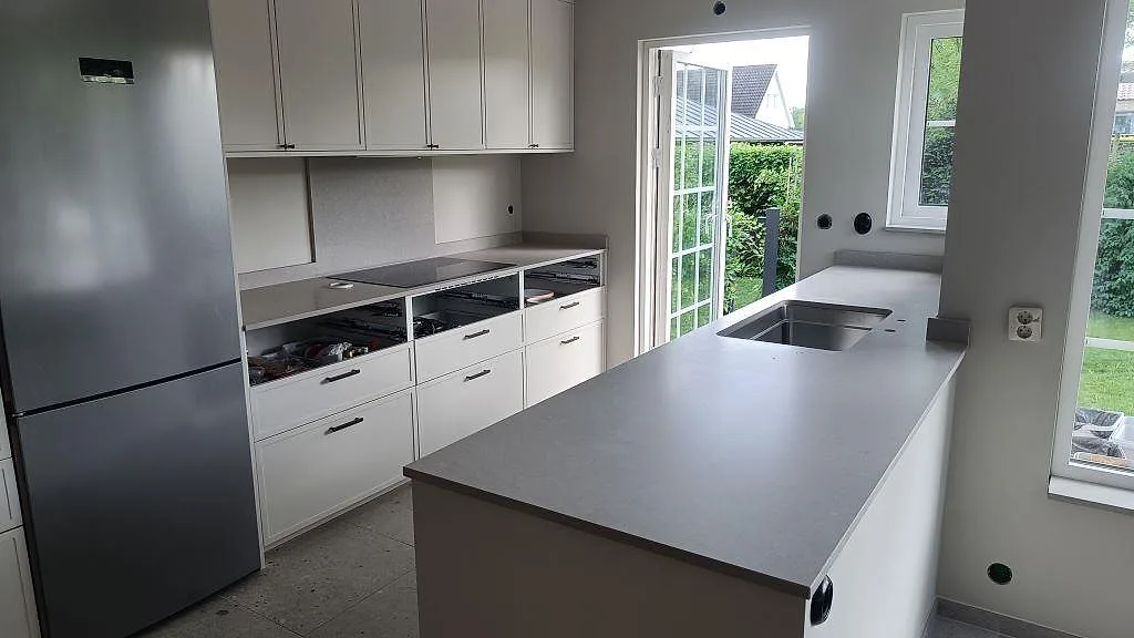 Köksbänkskiva i Caesarstone Clamshell, matt kvartskomposit, med stor köksö och underlimmad rostfri diskho i Södra Sandby.