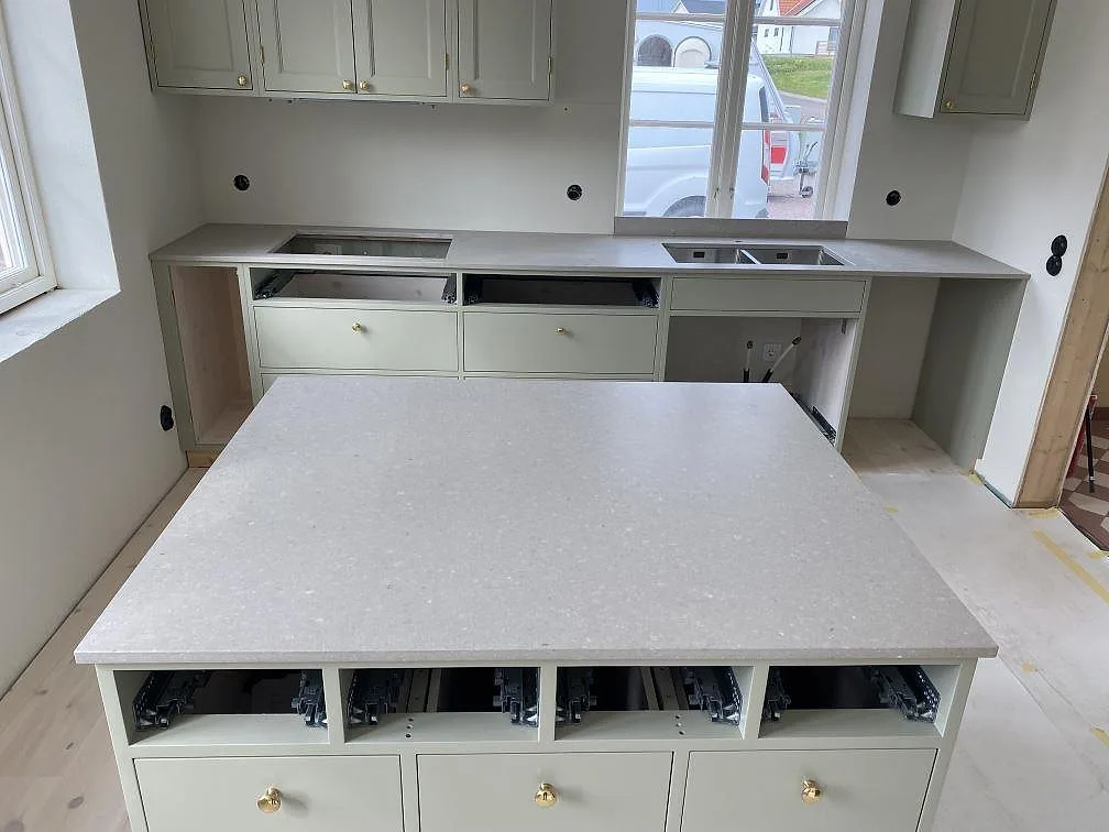 Köksbänkskiva i matt Caesarstone Clamshell komposit med stor köksö och bakre arbetsbänk i ett kök i Stehag.