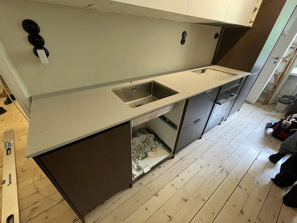 Köksbänkskiva i matt Caesarstone Clamshell, ljus beige kvartskomposit, med underlimmad diskho och hälluttag i ett kök i Stockholm.