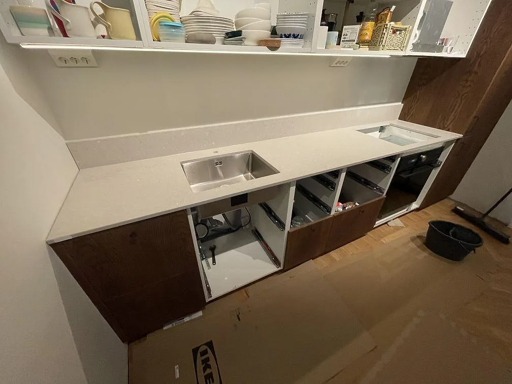 Köksbänkskiva i matt Caesarstone Clamshell, komposit, med rostfri diskho, låg stänkkant och hälluttag i ett kök i Stockholm.
