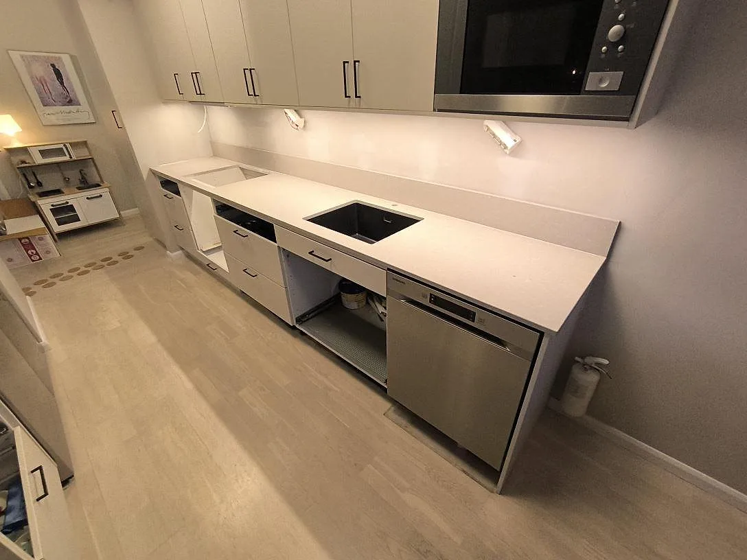 Köksbänkskiva i Caesarstone Clamshell, polerad kvartskomposit, med svart ho, hälluttag och låg stänkkant i ett kök i Stockholm.