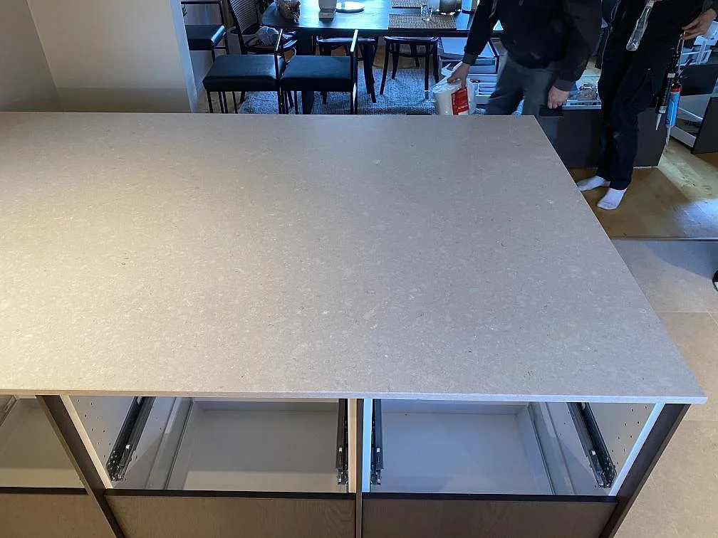 Detalj av köksö i Caesarstone Clamshell, polerad ljusgrå komposit, med skåpstommar under montering i Torslanda.