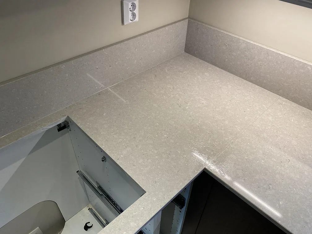 Hörndel av köksbänkskiva i Caesarstone Clamshell med låg stänkkant och polerad komposityta i Torslanda.
