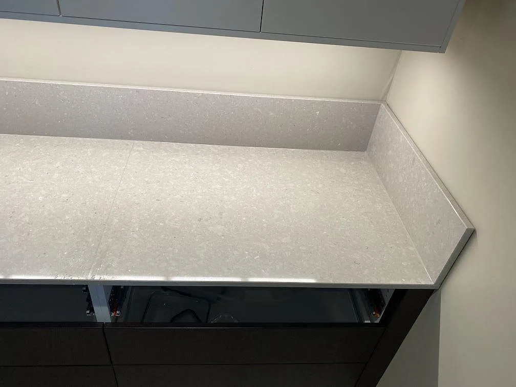 Rak bänkrad i polerad Caesarstone Clamshell med stänkkant och mörka underskåp under montering i Torslanda.