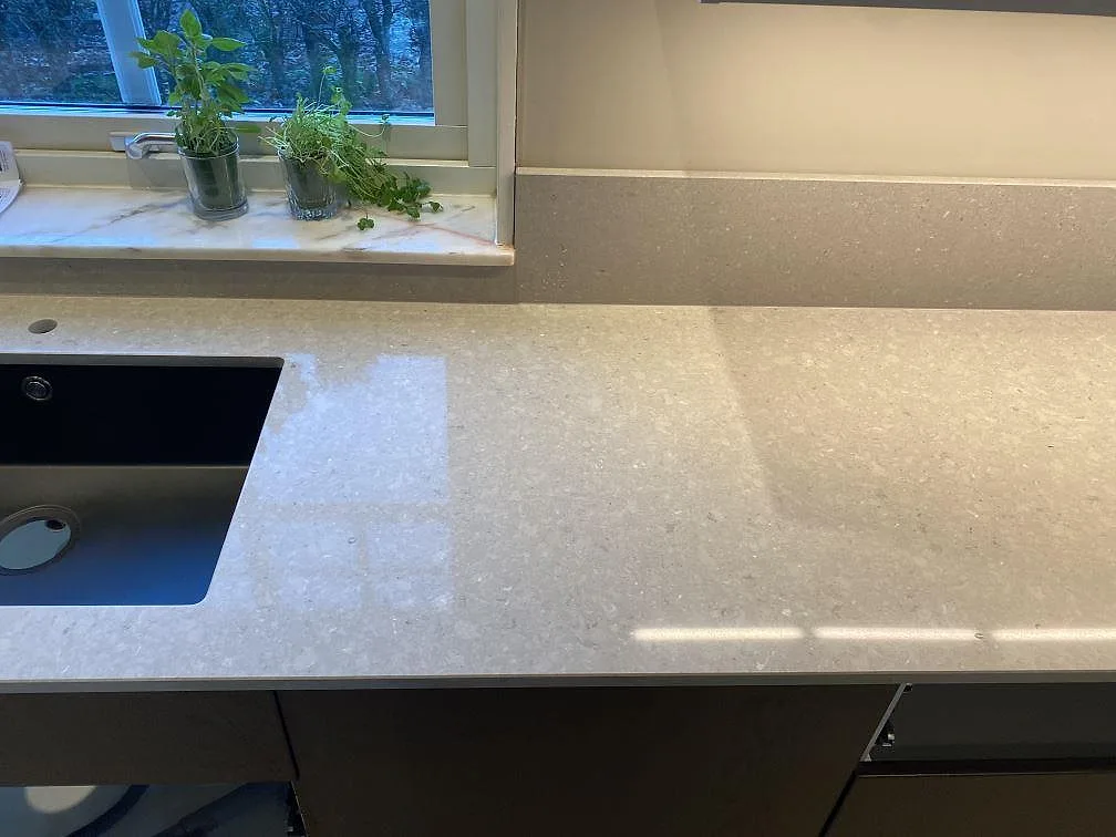 Ljusgrå Caesarstone Clamshell som köksbänkskiva med synlig diskho, stänkkant och polerad yta i Torslanda.