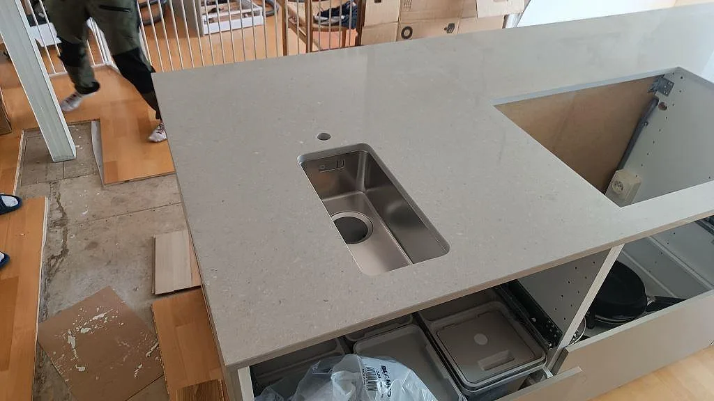 Köksö i Caesarstone Clamshell, polerad komposit, med underlimmad rostfri diskho och rektangulärt urtag i Torslanda.