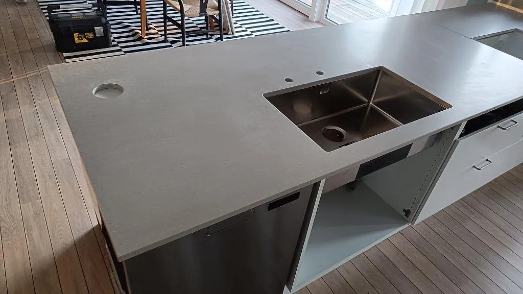 Närbild på matt Caesarstone Clamshell bänkskiva med underlimmad rostfri diskho och rund genomföring i kök på Torsö.