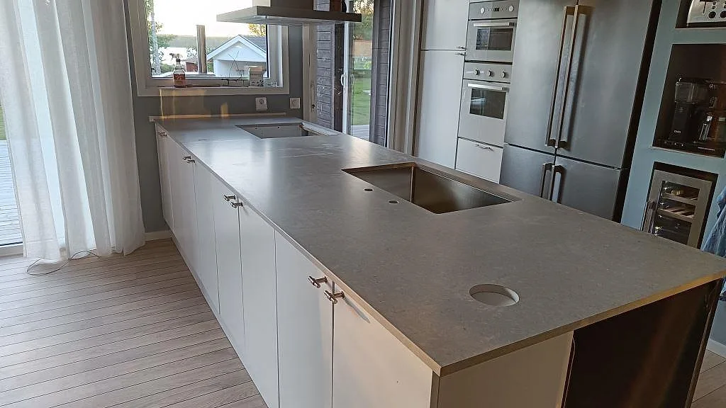 Monterad köksbänkskiva i 20 mm matt Caesarstone Clamshell med diskho, rund genomföring och köksöliknande arbetsyta på Torsö.