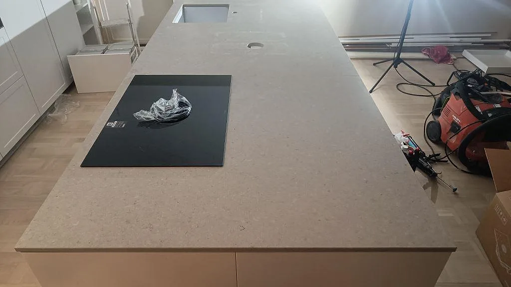 Topvy över den matta Caesarstone Clamshell-bänkskivan på köksarbetsytan med svart häll, diskho och kabelgenomföring i Västra Frölunda.