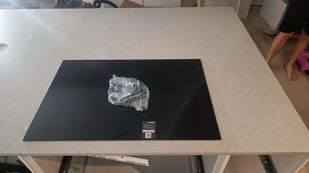 Detaljbild av svart häll i en ljus Caesarstone Clamshell-bänkskiva på öppna köksstommar i Västra Frölunda.