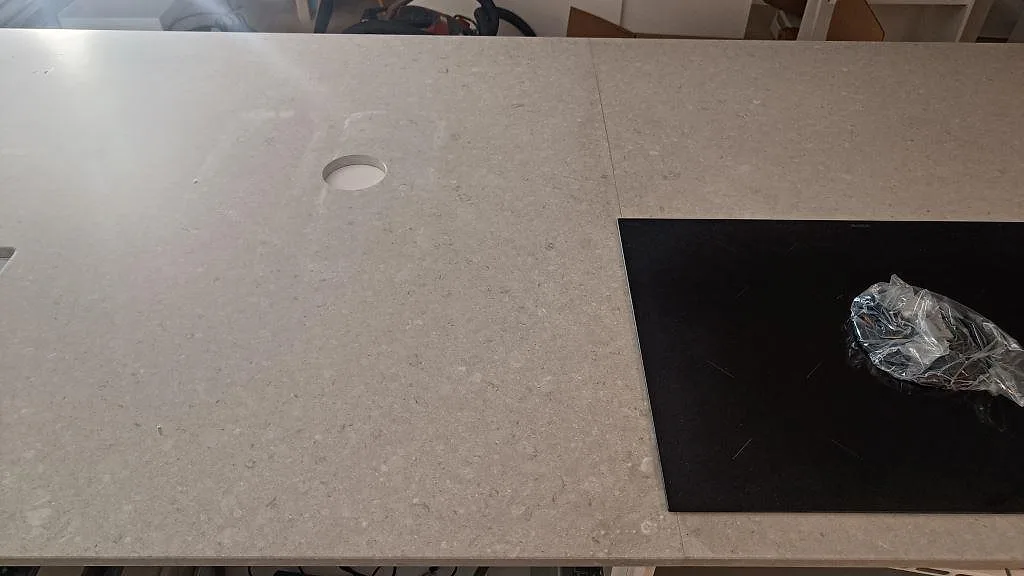 Närbild av svart induktionshäll monterad i Caesarstone Clamshell, matt kompositbänkskiva i Västra Frölunda.