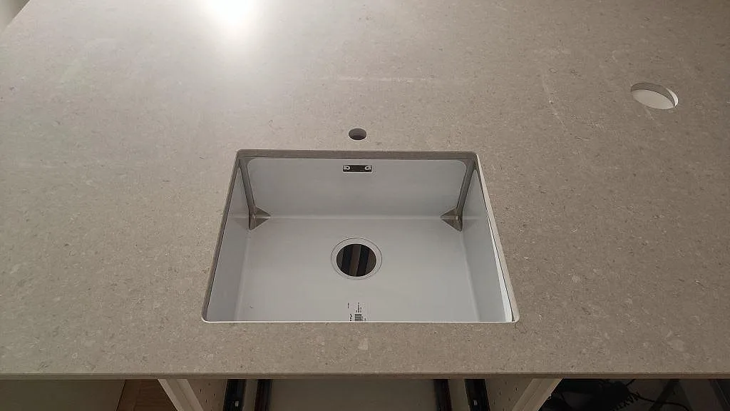 Närbild av underlimmad diskho i en matt Caesarstone Clamshell-kompositbänkskiva i kök i Västra Frölunda.