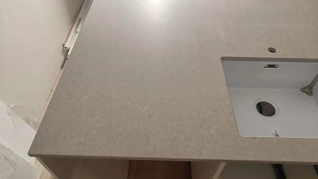 Matt Caesarstone Clamshell-bänkskiva med underlimmad diskho och öppen arbetsyta under montering i Västra Frölunda.