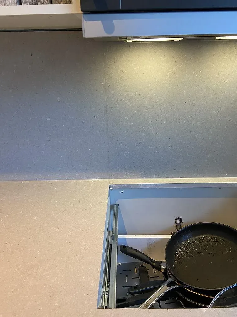 Närbild på den gräddvita Caesarstone Clamshell-bänkskivan med spräcklig struktur intill köksskåp i Växjö.