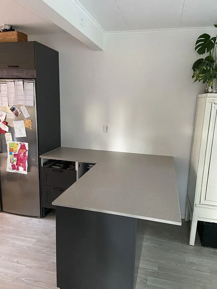 Köksbänkskiva i Caesarstone Clamshell med rostfri diskho och mörka bänkytor vid spissidan i ett kök i Växjö.