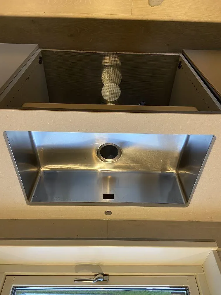 Köksbänkskiva i beige Caesarstone Clamshell, matt, med underlimmad rostfri diskho och blandarhål i ett kök i Varberg.