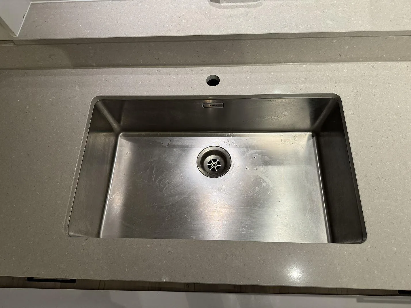 Detalj av rostfri diskho monterad under polerad Caesarstone Clamshell med blandarhål och ljus kvartskomposityta i Veinge.