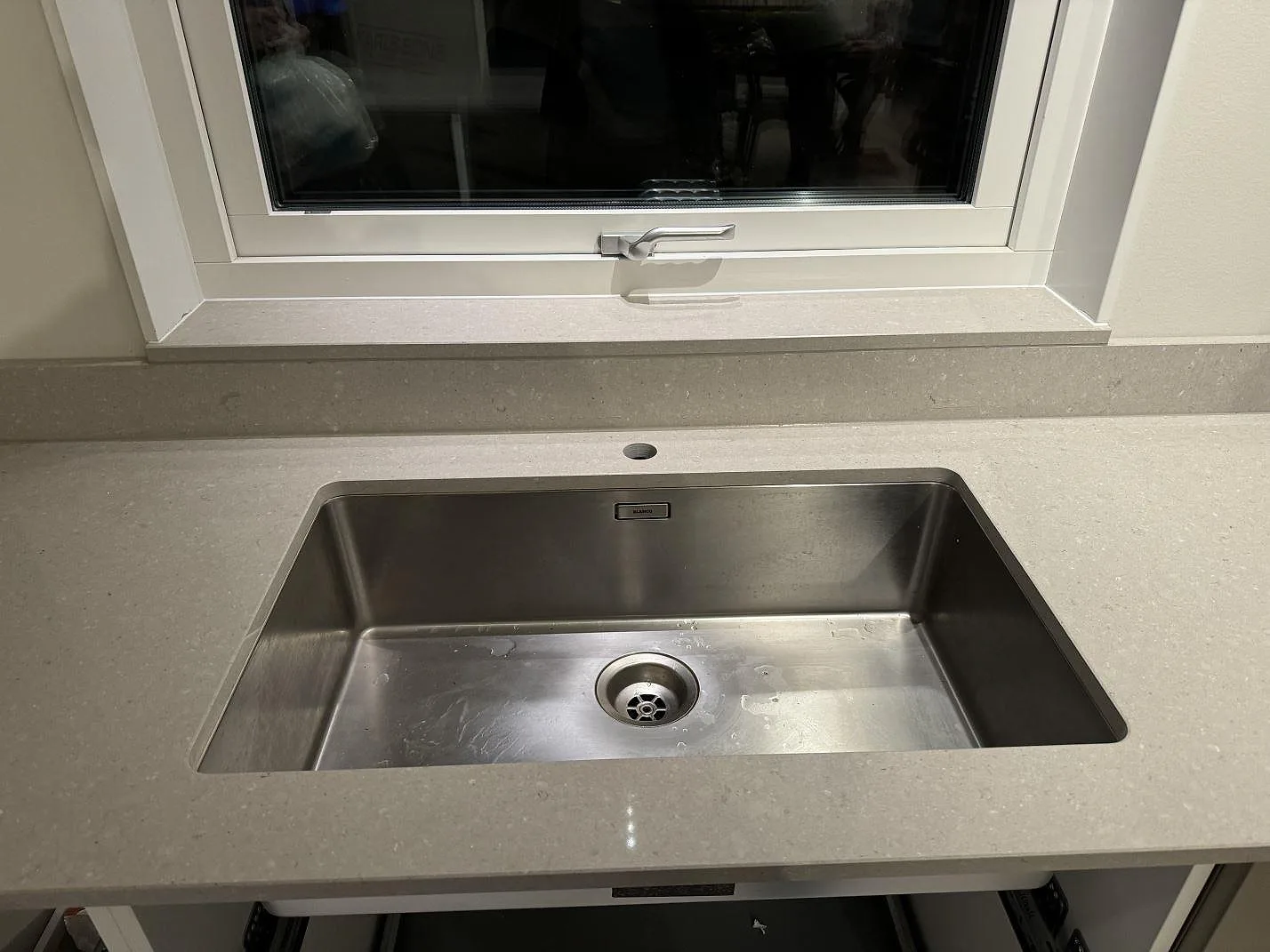 Köksbänk i Caesarstone Clamshell med underlimmad rostfri diskho, blandarhål och fönsterbänk i ett kök i Veinge.