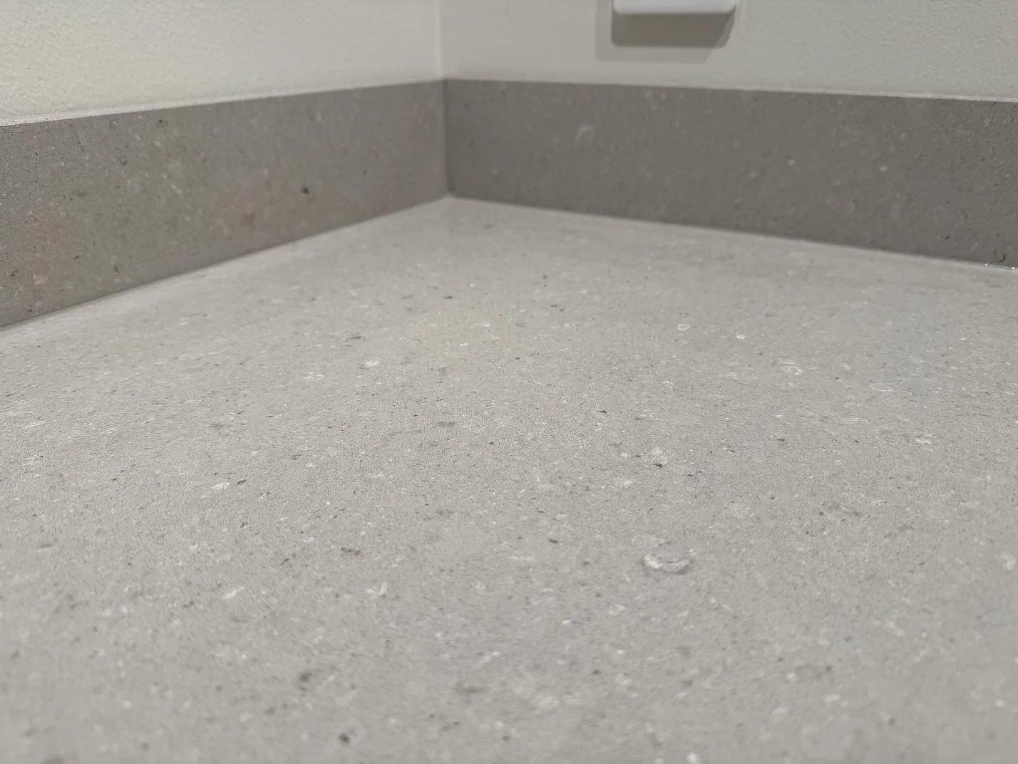 Närbild av polerad Caesarstone Clamshell kvartskomposit med låg stänkkant och diskret spräcklig yta i Veinge.