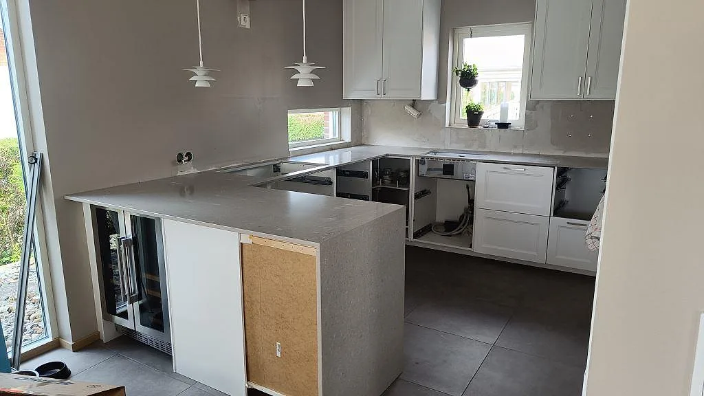 Köksbänkskiva och köksö i polerad Caesarstone Clamshell komposit i ett kök under montering i Viken.
