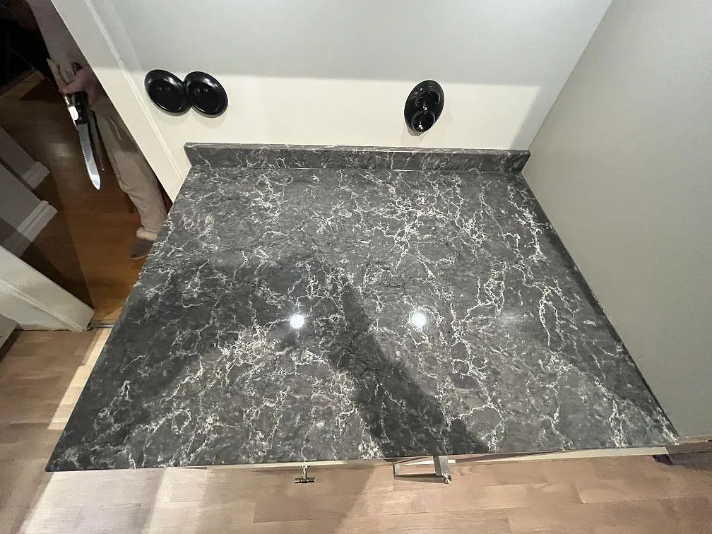 Detalj av polerad Caesarstone Coastal Grey med låg uppvikt stänkkant och tydlig marmorerad yta i Västerås.