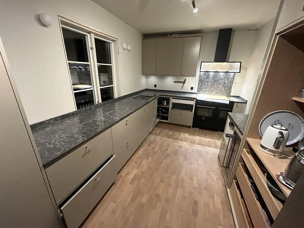 Köksbänkskiva i polerad Caesarstone Coastal Grey i L-format med mörk ådring i ett kök i Västerås.