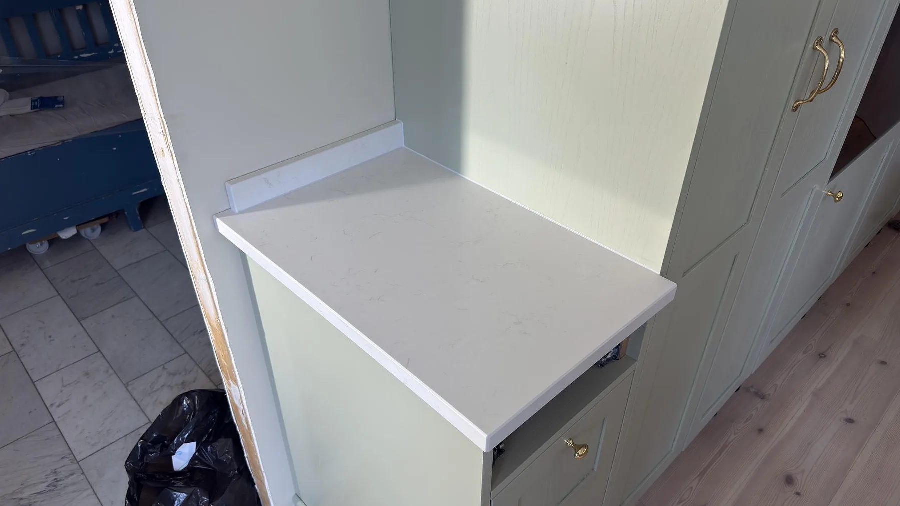 Solbelyst köksbänkskiva i polerad Caesarstone Frosty Carrina med diskret ådring i ett kök i Vaxholm.