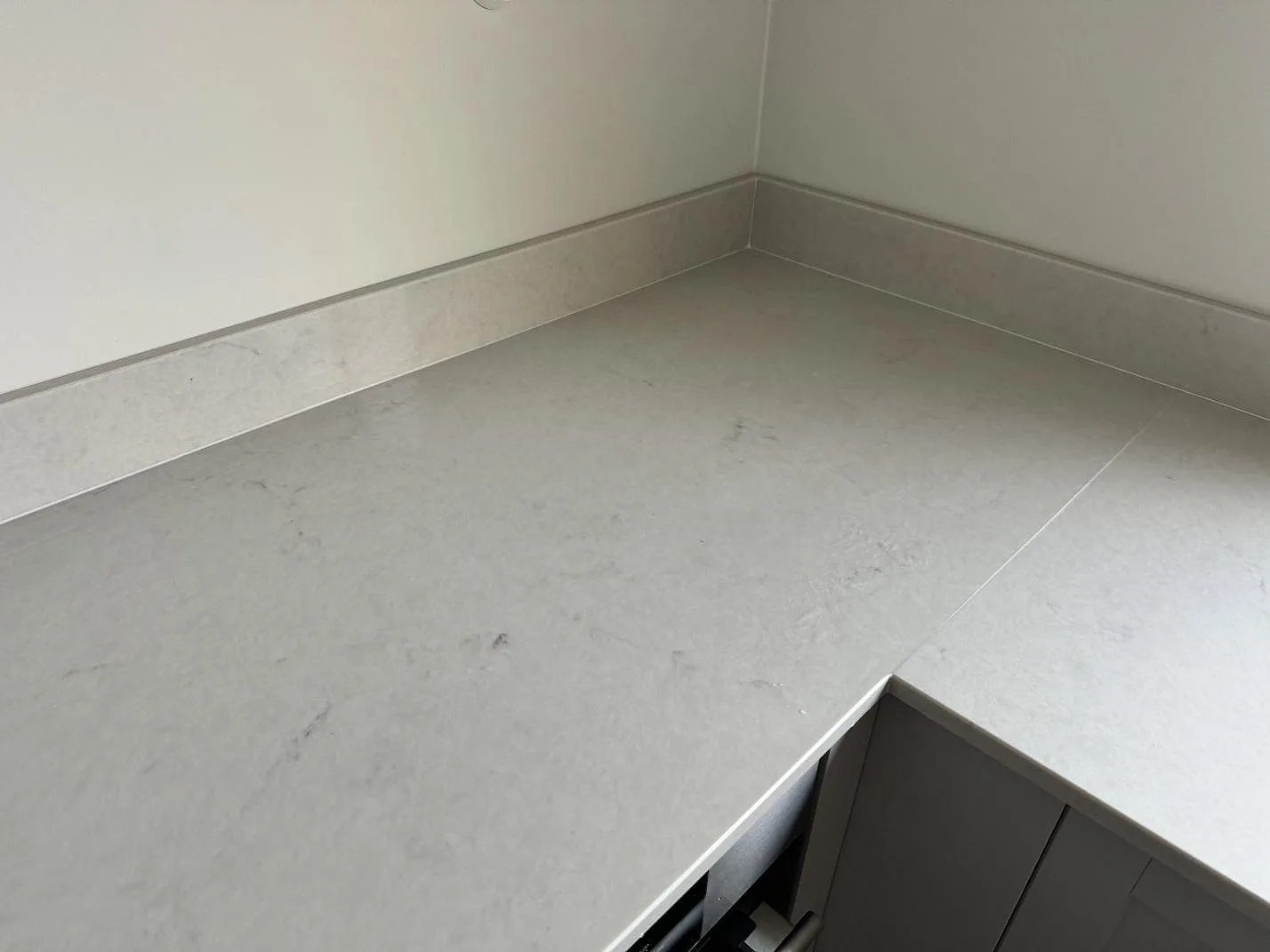 Köksbänkskiva i polerad Caesarstone London Grey komposit med ljus ådring och uppvikt stänkkant i ett kök i växjö.