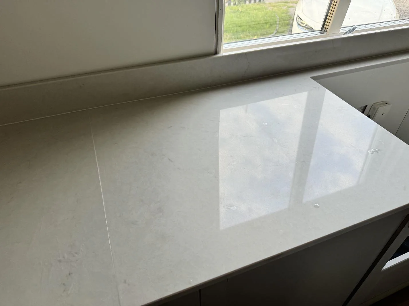 Polerad Caesarstone London Grey bänkskiva vid fönster med diskhålsuttag och ljus komposityta i växjö.