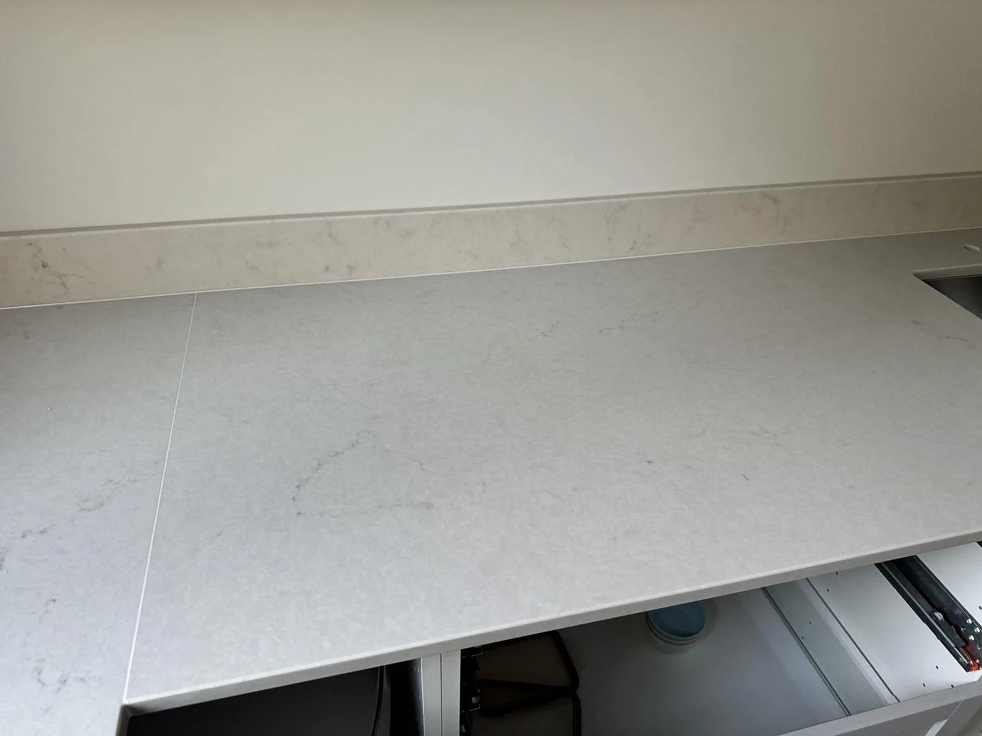 Ljus Caesarstone London Grey kompositbänkskiva med polerad yta, stänkkant och öppna köksstommar under montering i växjö.
