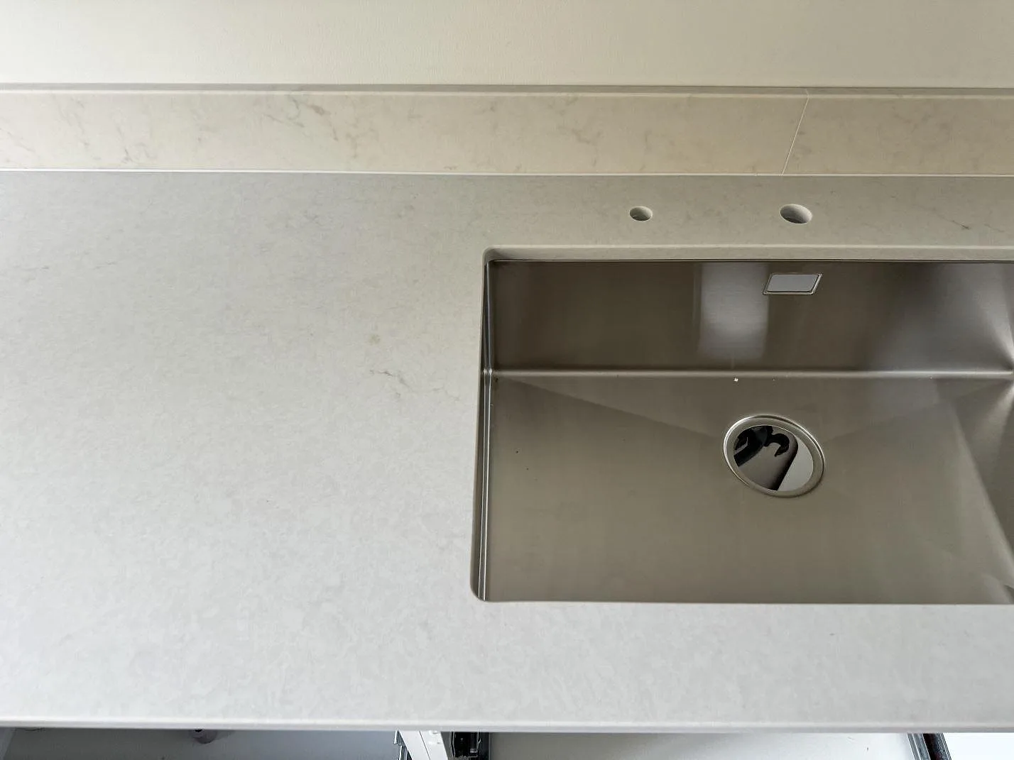 Närbild på polerad Caesarstone London Grey kompositbänkskiva med rostfri diskho och borrade blandarhål i växjö.
