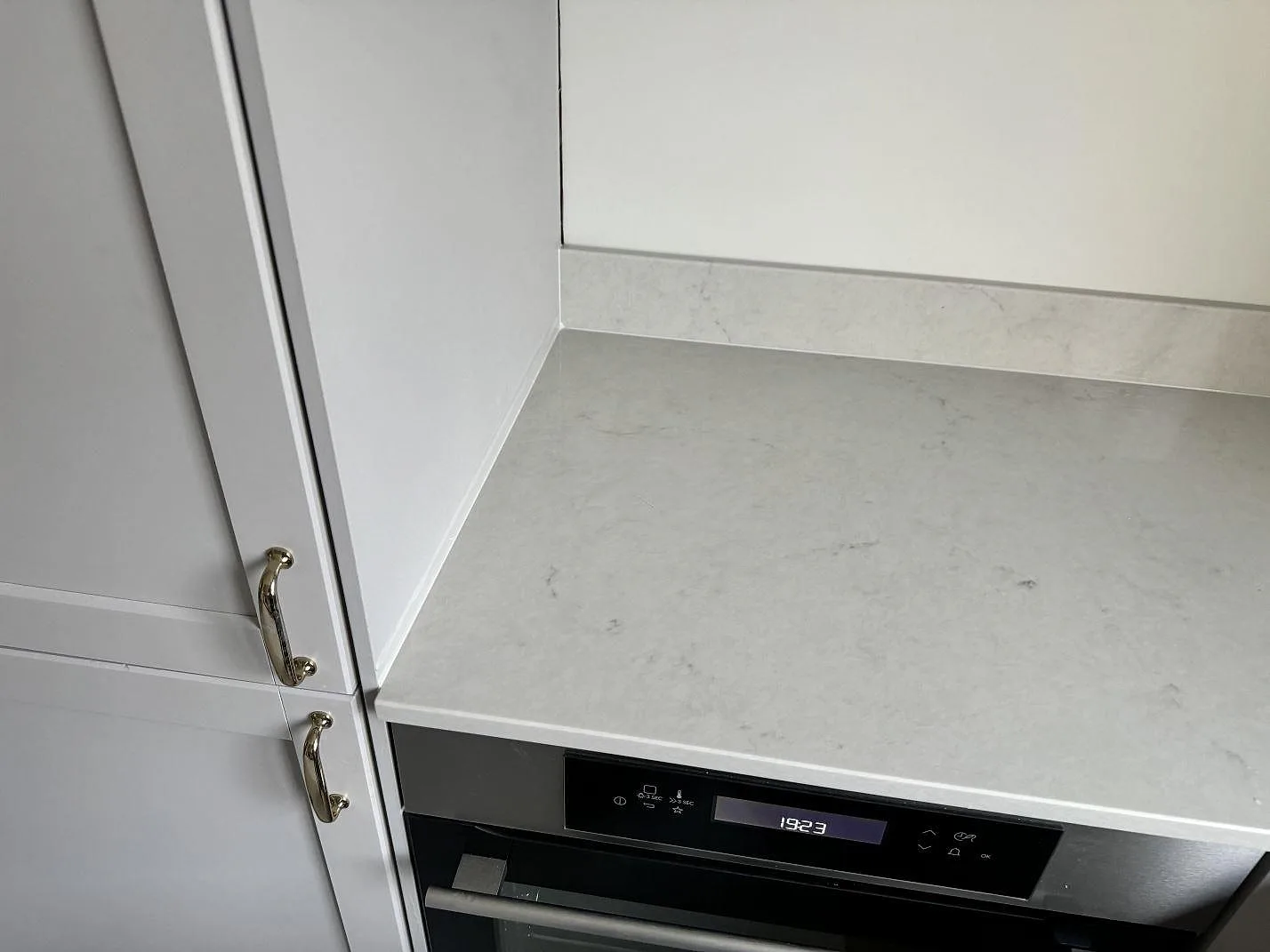 Köksbänkskiva i 20 mm polerad Caesarstone London Grey ovanför ugn med uppvikt stänkkant i växjö.