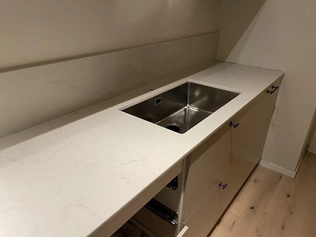 Lång köksbänk i Caesarstone London Grey med underlimmad rostfri diskho i ett kök i Vallentuna.