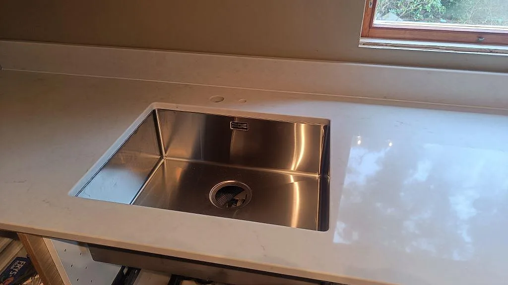 Underlimmad rostfri diskho infälld i polerad Caesarstone London Grey köksbänkskiva i ett kök i Varberg.