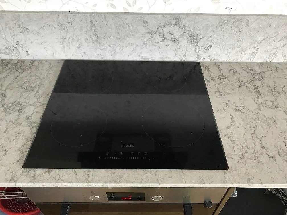 Köksbänkskiva i Caesarstone Moorland Fog med infälld Siemens induktionshäll och mjuk grå ådring i ett kök i Bohus.