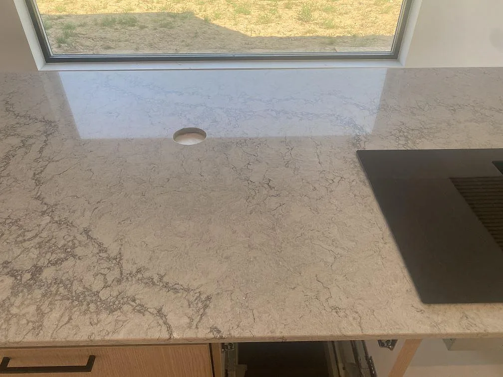Närbild på polerad Caesarstone Moorland Fog som köksbänkskiva med mjuk grå ådring och svart hällkant i Farhult.