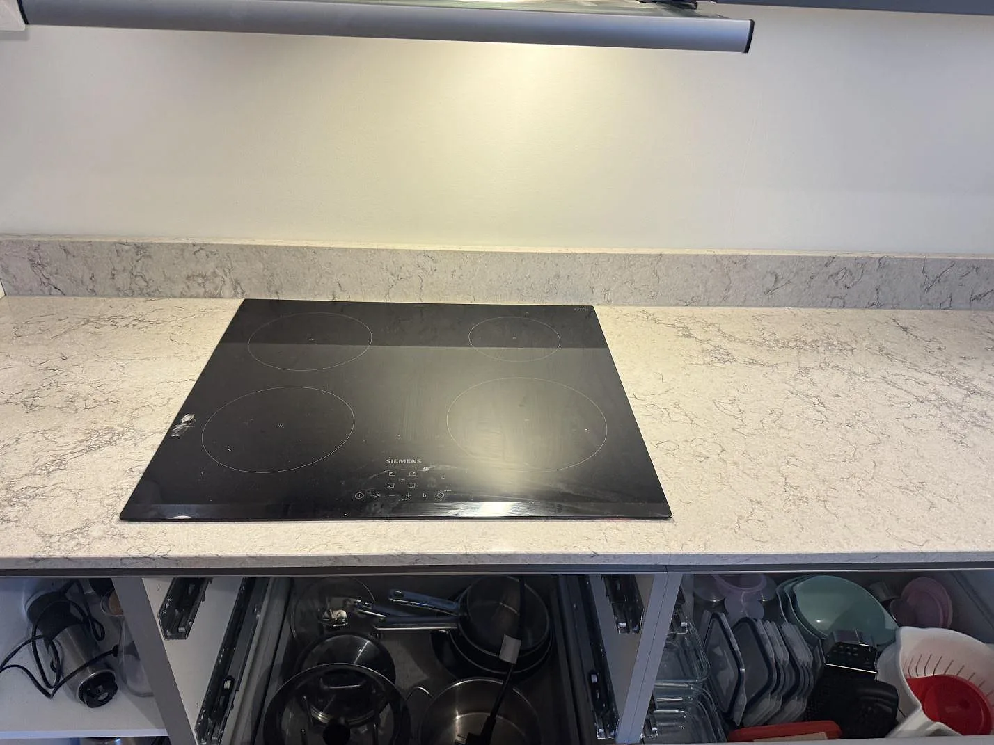 Ovanifrån på Caesarstone Moorland Fog köksbänkskiva med infälld induktionshäll och grå ådring i ett kök i Göteborg.