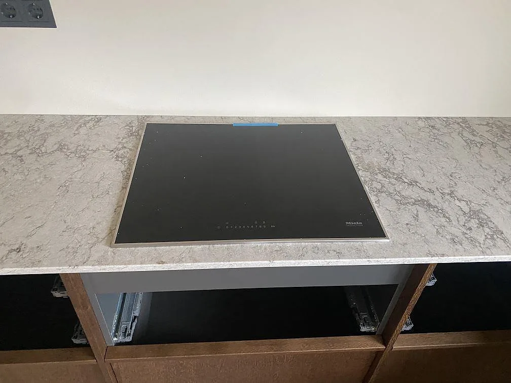 Infälld induktionshäll i köksbänkskivan av Caesarstone Moorland Fog i Grebbestad, sedd ovanifrån.