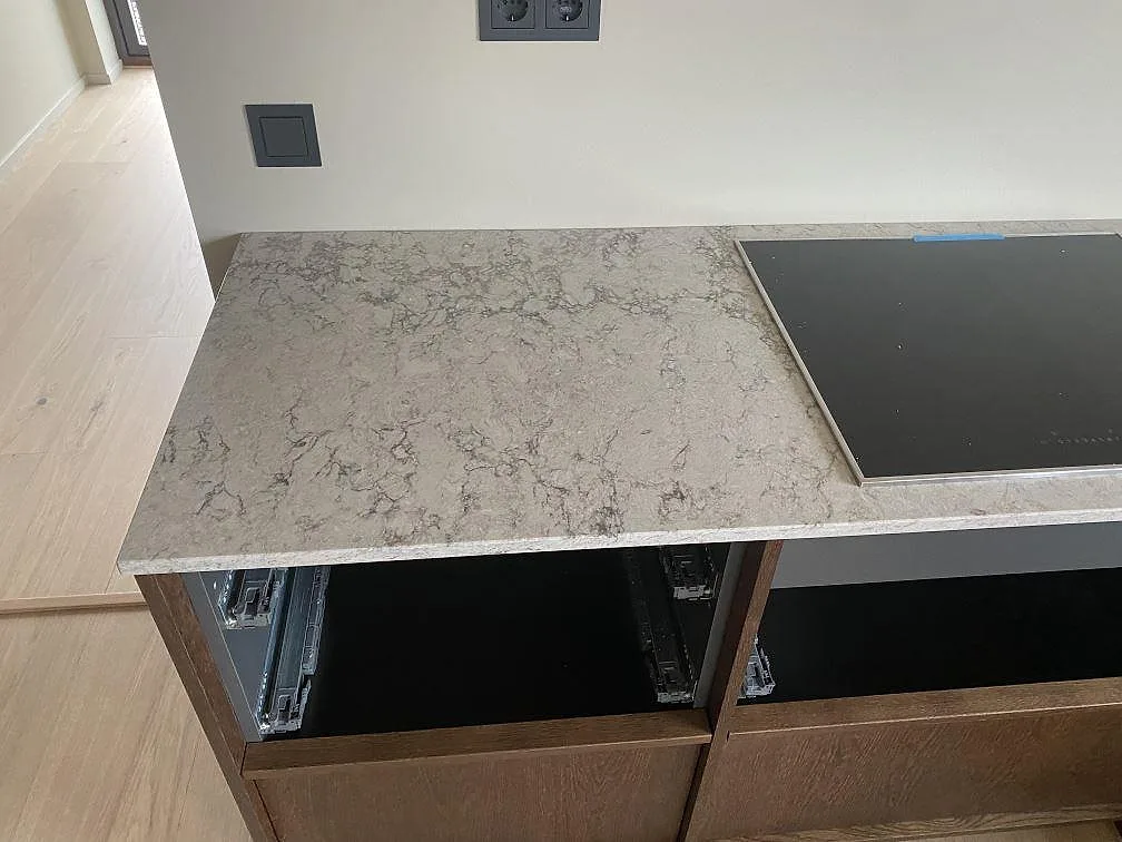 Köksbänk i grå Caesarstone Moorland Fog i Grebbestad med infälld induktionshäll och spräcklig ådring i den polerade ytan.