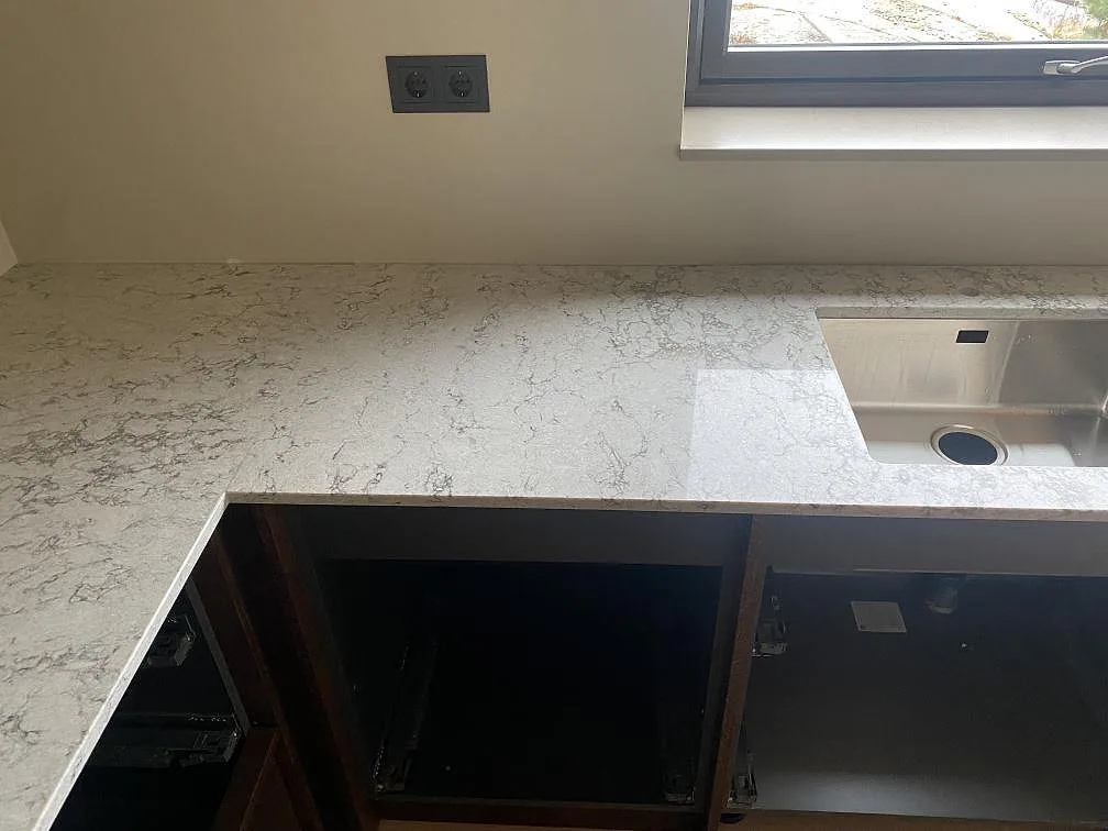 Polerad köksbänkskiva i Caesarstone Moorland Fog i Grebbestad med rostfri diskho och fin grå ådring i stenen.