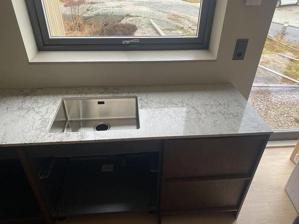 Köksbänkskiva i Caesarstone Moorland Fog under fönstret i Grebbestad med underlimmad rostfri diskho, fotad under montering.