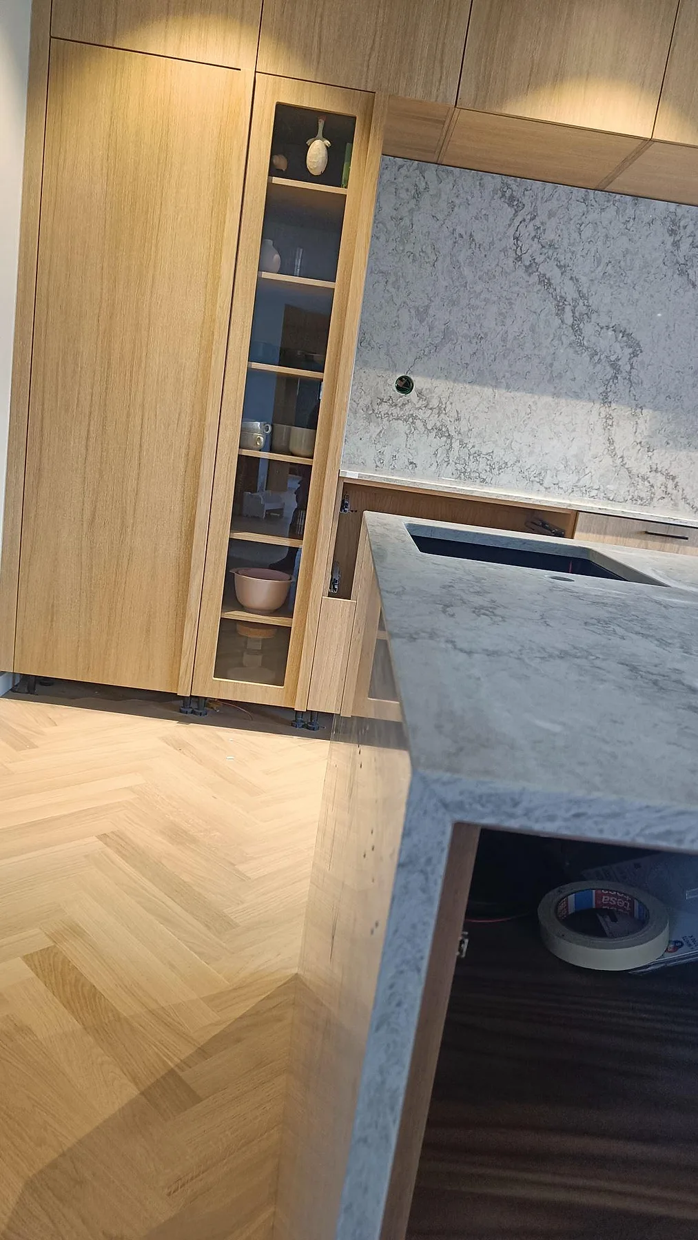 Detalj av polerad Caesarstone Moorland Fog med stänkskydd, träskåp och köksö under montering i Höllviken.