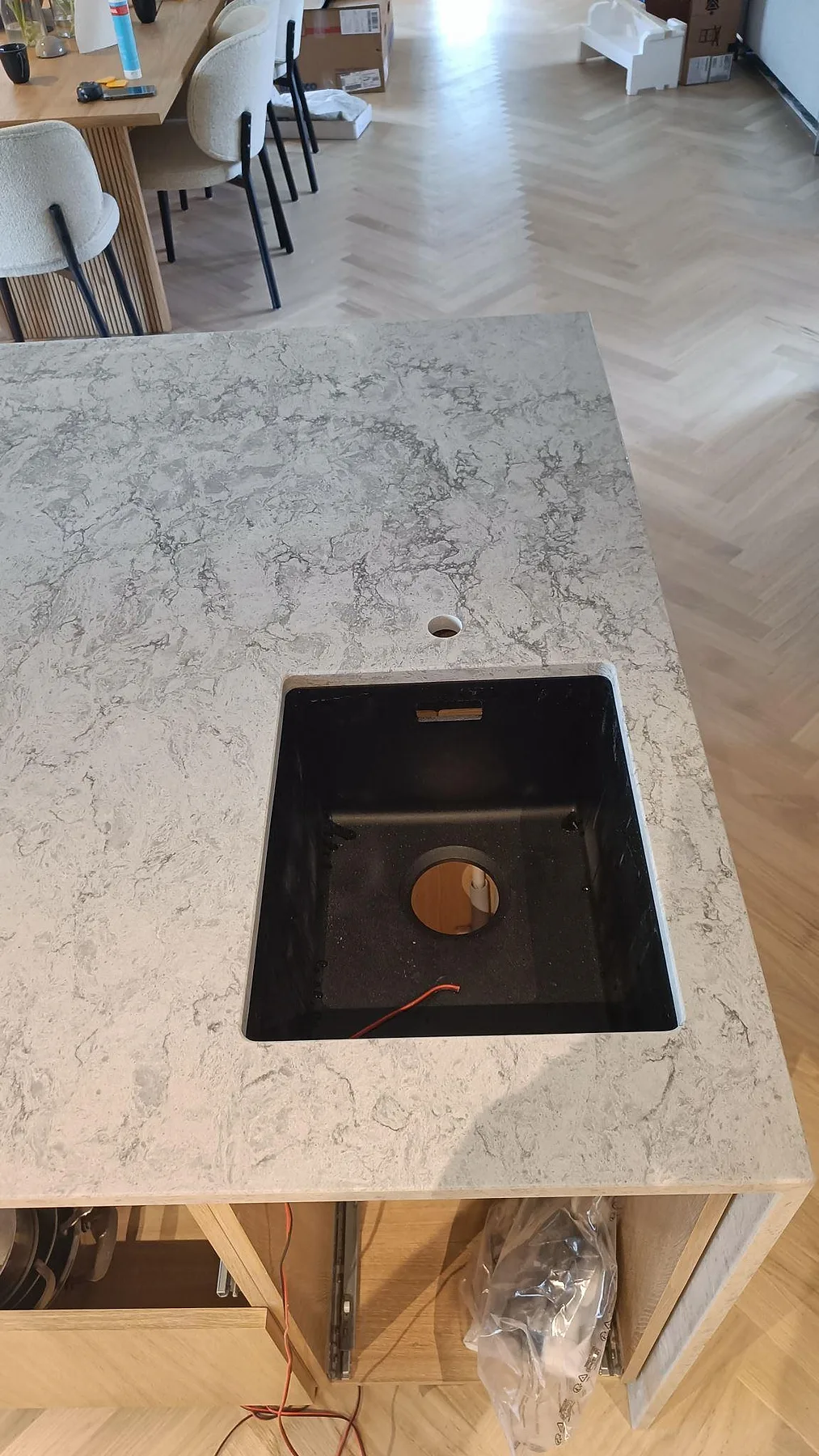 Närbild på svart underlimmad diskho i polerad Caesarstone Moorland Fog på en köksö i Höllviken.
