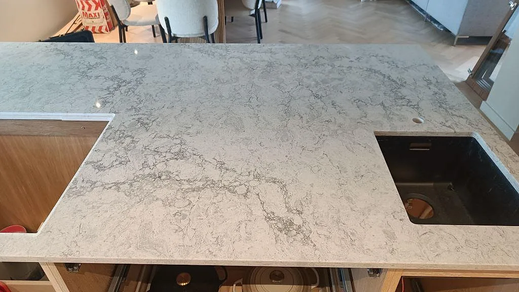 Bänkskiva i polerad Caesarstone Moorland Fog med svart diskho och stort urtag i en köksö i Höllviken.