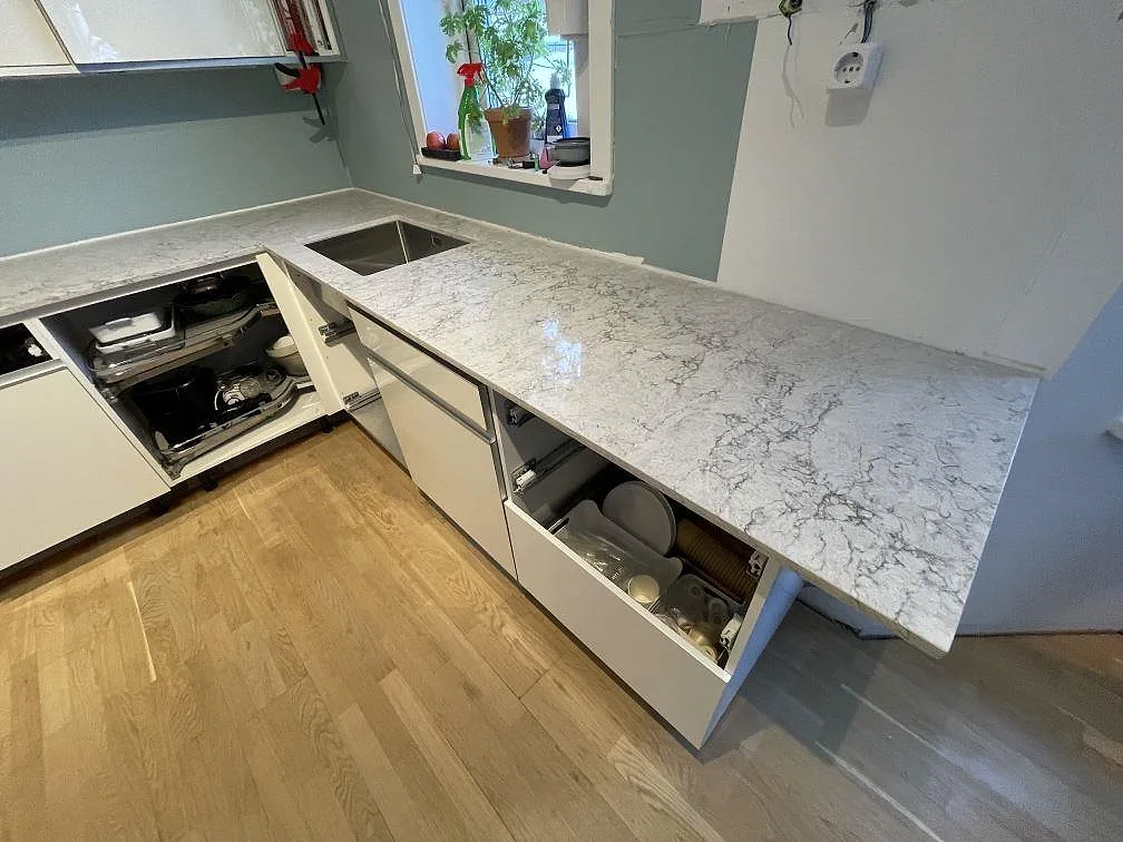 Polerad köksbänkskiva i Caesarstone Moorland Fog med underlimmad diskho i rostfritt stål i ett kök i Huddinge.